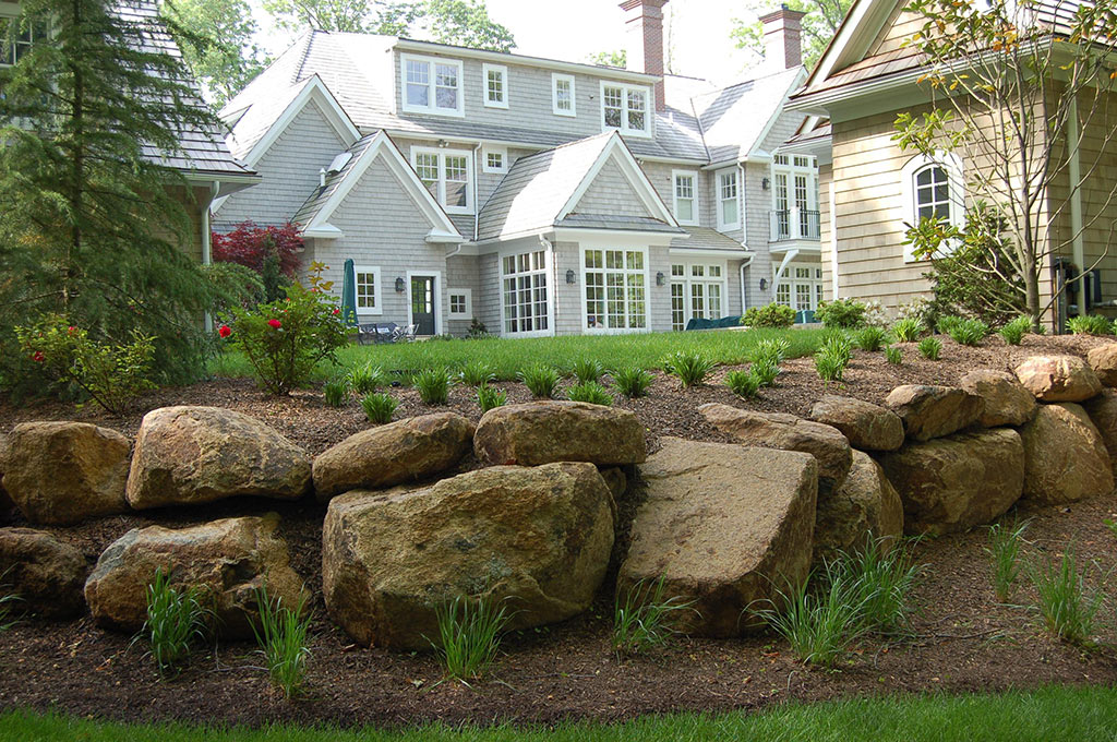 stone wall with landscaping in front of a house